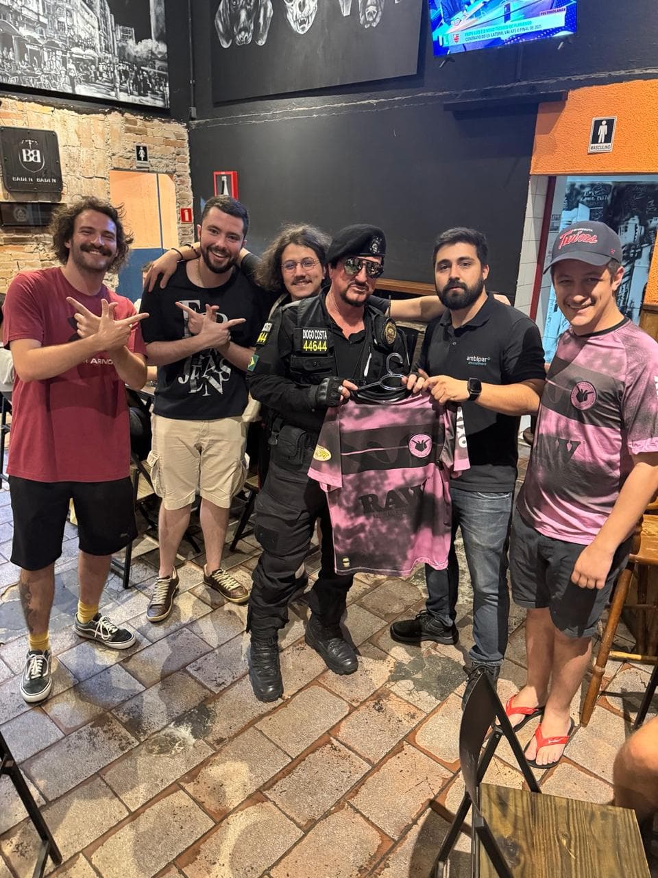Sócios apresentam a nova camisa ao lado de um policial sorridente